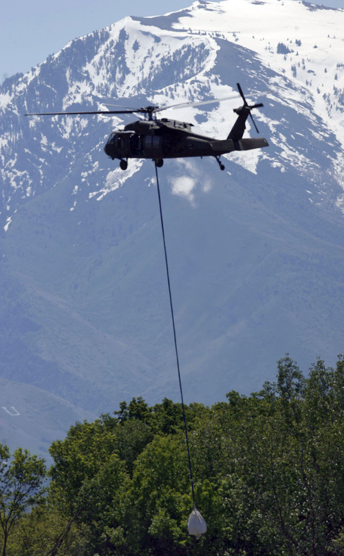 Francisco Kjolseth  |  The Salt Lake Tribune
With much snow still in the mountains, large sandbags are moved by Black Hawk helicopters in an effort to shore up a broken levee. Weber County's Incident command manages the repairs along the Weber River in West Warren on Friday, June 10, 2011, with help from the Utah National Guard and contractor Randy Marriott Construction. Two black hawk helicopters were brought in to move large sand bags into the area while ground crews try to shore up the area that breached to hold the bags in place.