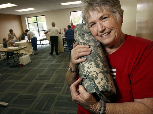 Scott Sommerdorf  |  The Salt Lake Tribune
Jackie Bulloch hugs one of the finished quilts that will be sent to members of the Utah National Guard's 222nd Field Artillery Unit. Bulloch, a Cedar City woman who has three grandsons and a nephew in the 222nd, organized a project to make quilts from special Army-issued camo fabric. She and other sewing volunteers worked at the 222nd Armory in Richfield on Monday.