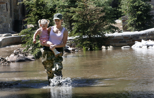 Scott Sommerdorf  |  The Salt Lake Tribune
Robyn Funcannon carries her 2-year-old daughter Cambrie across some of the floodwater near her father's property along the Weber River on Saturday.