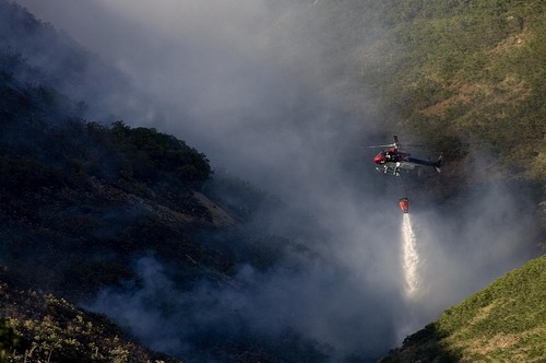 Djamila Grossman  |  The Salt Lake Tribune

A helicopter drops water on flames as a wildfire burns in the hills above the University of Utah Research Park in Salt Lake City, Utah, on Sunday, July 3, 2011.