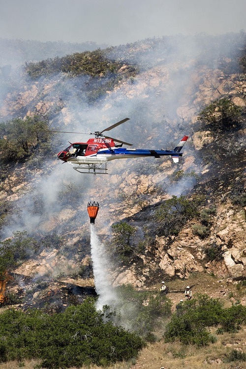 Djamila Grossman  |  The Salt Lake Tribune

A helicopter drops water on flames, as firefighters work on a wildfire that burns in the hills above Red Butte Garden and the new Utah Museum of Natural History in Salt Lake City, Utah, on Sunday, July 3, 2011.