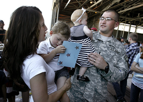 Scott Sommerdorf  |  The Salt Lake Tribune
Angie Becker of Bountiful holds her 3-year-old son Jaxon as her husband, Lt. Ryan Becker, holds his 10-month-old daughter Mya who he is seeing for the first time. Mya was born during Lt. Becker's deployment in Afghanistan with the Utah National Guard's 118th Engineer (Sapper) Company. The unit returned Sunday, July 10, 2011, from its 12-month deployment. The mission of the unit was to provide route-clearance support to Coalition forces in Afghanistan.