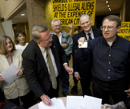 Al Hartmann  |  The Salt Lake Tribune  
Merrill Cook, left, signs a petition to file at the Salt Lake County Clerk's office Tuesday to put measure on 2012 ballot for penalizing companies for hiring undocumented workers and getting rid of HB 116. Eli Cawley, right, of Utah Minuteman Project shows his Utah drivers license to crowd before signing the petition.