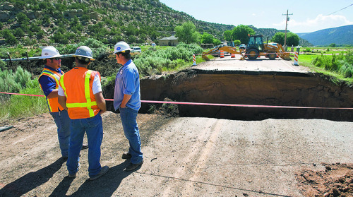 Al Hartmann  |  The Salt Lake Tribune
UDOT workers and road contractors check out a 25 foot deep 40 foot wide hole on Highway 35 about 3 miles south of Tabiona Thursday morning.  A sudden hail storm Wednesday night brought  debris down a dry wash, clogging a culvert below the road and undermining the soil beneath the road causing it to wash out.