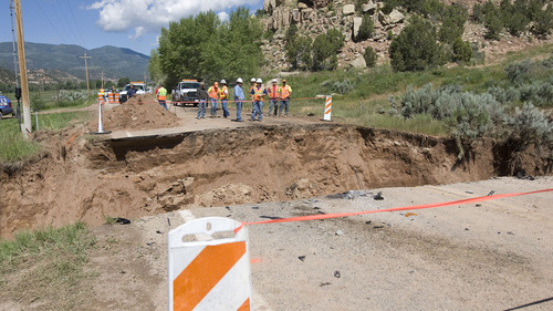 Al Hartmann  |  The Salt Lake Tribune
UDOT workers and road contractors check out a 25-foot-deep 40-foot-wide hole on Highway 35 about 3 miles south of Tabiona on Thursday morning. A sudden hail storm Wednesday night brought debris down a dry wash, clogging a culvert below the road and undermining the soil beneath the road, causing it to wash out.