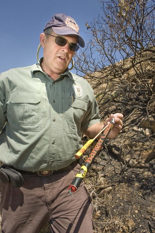 Paul Fraughton  |  The Salt Lake Tribune
Unified Fire Authority investigator Ren Egbert, at the site of a hillside fire near Pete's Rock at the trailhead to Mt. Olympus, shows fireworks Thursday similar to the ones found at the scene.