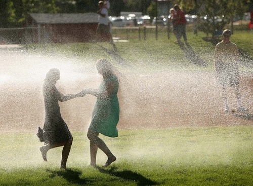 Leah Hogsten  |  The Salt Lake Tribune
Friends Erin Spencer and Yazmine Baker of Draper play in the fire hose spray at Draper City Days. Cities are facing shrinking budgets, especially for nonessential services like entertainment events and festivals. But in the down economy, more families are looking for free or low-cost events.