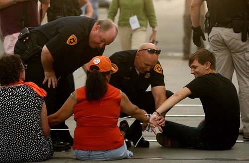 Leah Hogsten  |  The Salt Lake Tribune
Protesters' plastic ties are cut apart so that police officers can walk each protester out of the intersection to be arrested. Police arrested 26 people during a demonstration that blocked traffic along Main Street on Tuesday in Salt Lake City.