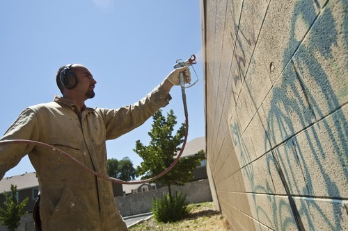 Chris Detrick | The Salt Lake Tribune 
Jacob Shafizadeh paints over graffiti on a wall in West Valley City Thursday July 21, 2011. His job is to remove graffiti from major roadways and public property.