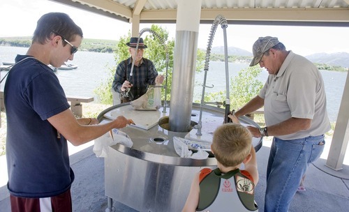 Paul Fraughton  |  The Salt Lake Tribune
Jakob Freestone, 15, left, Easton Jacobsen, 6, Howard Freestone  and Lee Johnson clean their catch at a cleaning station at Hyrum State Park on June 28.