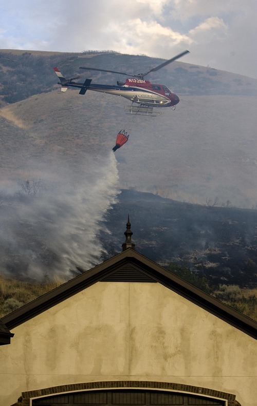 Djamila Grossman  |  The Salt Lake Tribune

A helicopter drops water on flames of a fire that burns above homes in Draper, Utah, on Saturday, Aug. 13, 2011. The fire threatened several homes but destroyed none.