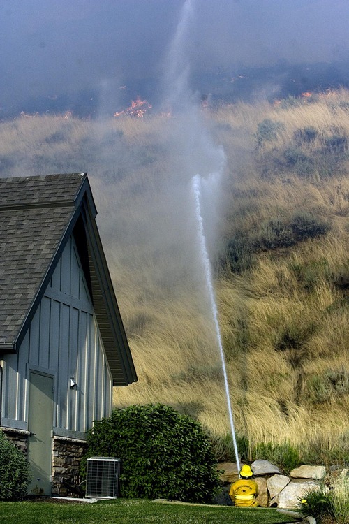 Djamila Grossman  |  The Salt Lake Tribune

A firefighter shoots water at flames as a fire burns in the hills above in Draper, Utah, on Saturday, Aug. 13, 2011. The fire threatened several homes but destroyed none.