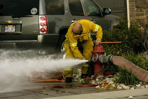 Djamila Grossman  |  The Salt Lake Tribune

A firefighter hooks up a hose to a hydrant as a fire burns in the hills above Draper, Utah, on Saturday, Aug. 13, 2011. The fire threatened several homes but destroyed none.