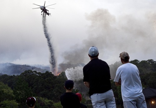 Djamila Grossman  |  The Salt Lake Tribune
Residents watch as a helicopter drops water on a fire that burns in the hills above their homes in Draper on Saturday. The fire threatened several homes but destroyed none.