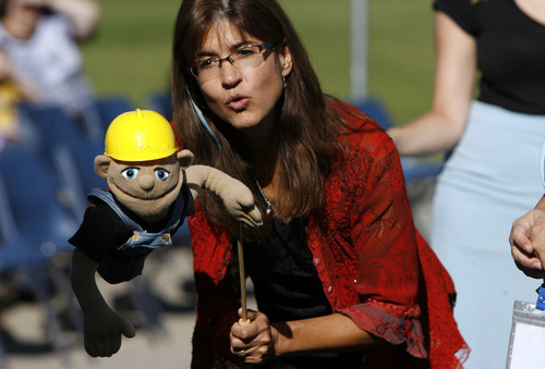 Francisco Kjolseth  |  The Salt Lake Tribune
Nicole Stoddard, a certified playground safety inspector, uses a puppet to teach students about the work behind the creation of a new playtround for the students at the Jean Massieu School of the Deaf in Salt Lake City on Monday, August 22, 2011. The school celebrated the unveiling with the help of Slyde the Playground Hound. Last week, vandals painted the playground with blue graffiti, but community volunteers cleaned up the $155,000 playground before the unveiling. Kids at the school pitched in $55,000 through fundraising to make it all happen.