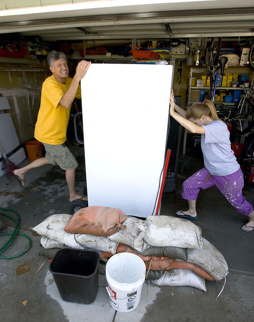 Al Hartmann  |  Tribune file photo
Greg Sloan, left, helped neighbor Cheryl Leithead to move a refrigerator from her wet garage after a late July thunderstorm whose floodwaters resulted in Salt Lake County establishing a $165,000 fund to help residents pay for damages.