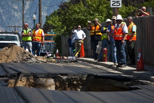 Chris Detrick  |  The Salt Lake Tribune
Wagstaff Crane Service works to pull a steam roller out of a sink hole Wednesday, Aug. 24, 2011. Orem city construction crews were working at 1200 North near 1150 West and smoothing the asphalt. About 10 a.m., a 12-foot-deep sink hole appeared in the freshly paved asphalt, said Orem police Sgt. Craig Martinez.