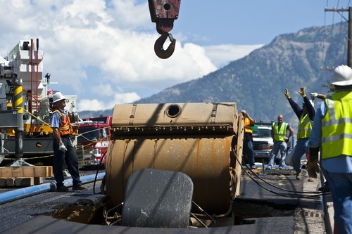 Chris Detrick  |  The Salt Lake Tribune
Wagstaff Crane Service works to pull a steam roller out of a sink hole Wednesday, Aug. 24, 2011. Orem city construction crews were working at 1200 North near 1150 West and smoothing the asphalt. About 10 a.m., a 12-foot-deep sink hole appeared in the freshly paved asphalt, said Orem police Sgt. Craig Martinez.
