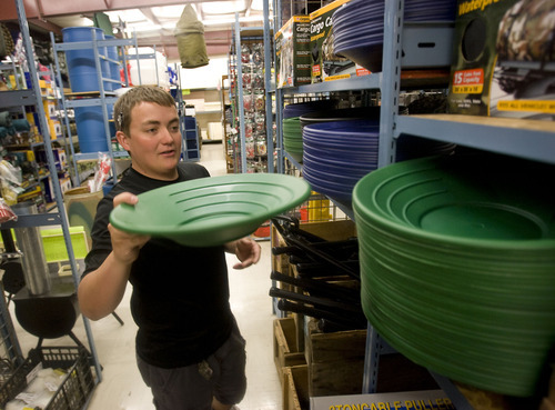 Al Hartmann  |  The Salt Lake Tribune
General Army Navy Outdoor store employee Tavey Sullivan stacks shelves with gold pans. The Taylorsville store, which sells surplus merchandise and other items, has been experiencing a run of sorts on its gold pans and rock picks.