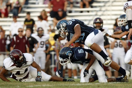 Chris Detrick  |  The Salt Lake Tribune
Layton's Tyler Fox (5) falls over Layton's Miller Toa (30) during the game at Layton High School Friday August 26, 2011.