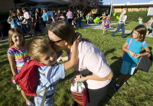 Al Hartmann  |  The Salt Lake Tribune
Veronica Bach kisses her children Mackenzie, left,  Alexander and Scarlet, goodbye at the entrance to Arcadia Elementary at 3461 W. 4850 South in Taylorsville on Wednesday, Aug. 31.   Students, parents, school officials and UDOT kicked off 