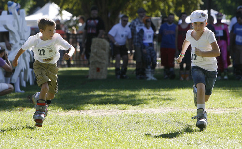 Francisco Kjolseth  |  The Salt Lake Tribune
Finn Ricketts, 8, left, keeps an eye on the competition as Malisia Taylor, 7, pulls ahead as the two youngsters get a head start in the first ever Yeti Pass Skootch'n Dash  at the Downtown Farmers on Saturday, September 3, 2011, wearing ski boots.