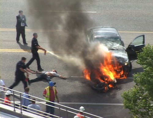 In this Monday, Sept. 12, 2011 image taken from video, police officers extinguish flames on a BMW and motorcycle that collided on U.S. 89 in Logan, Utah, as Brandon Wright lies on the ground between them. Wright was rescued by a group of strangers who tilted the BMW and pulled Wright, who was pinned underneath, to safety. Authorities said Wright was riding his motorcycle near the Utah State University campus in Logan when the 21-year-old collided with the BMW that was pulling out of a parking lot. Tire and skid marks on the highway indicate that Wright laid the bike down and slid along the road before colliding with the car, Assistant Police Chief Jeff Curtis said. (AP Photo/Chris Garff)