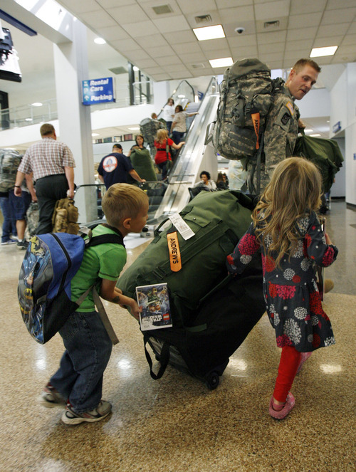 Francisco Kjolseth  |  The Salt Lake Tribune
Lending their dad a helping hand, Braxton Andews, 6, left, and Kari, 4, push Brian Andrews' bag after arriving in the first wave of approximately 40 soldiers from the 971st Medical Logistics Company (Army Reserve). The company from Ogden returned from deployment to Afghanistan on Wednesday, Sept. 21, 2011, at Salt Lake City International Airport. The 971st Medical Company's one-year mission was mostly the shipping and receiving of medical supplies.
