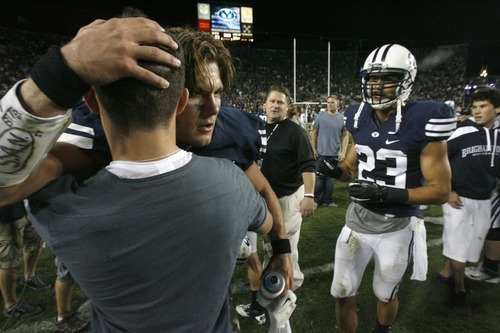 Rick Egan  | The Salt Lake Tribune 

  Brigham Young Cougars quarterback Riley Nelson (13) celebrates with fans after the game, as BYU defeated Utah State, 27-24 in Provo, Friday, September 30, 2011.  Brigham Young Cougars wide receiver Cody Raymond is on the right.