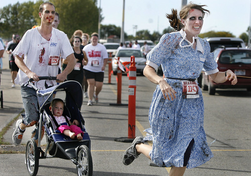 Scott Sommerdorf  |  The Salt Lake Tribune             
Zombie runners make their way around the Utah Fairpark parking lot during the running of the Night of the Running Dead on Saturday. Zombie runners chased human runners after giving them a two-minute head start.