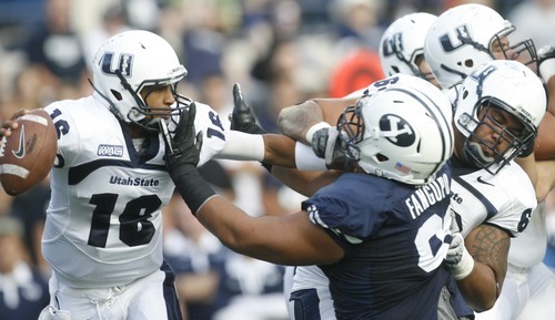 Rick Egan  | The Salt Lake Tribune 

Utah State Aggies quarterback Chuckie Keeton (16) looks for a receiver as he gets pressure from Brigham Young Cougars defensive lineman Hebron Fangupo (91) in football action, BYU vs Utah State,  in Provo, Friday, September 30, 2011.