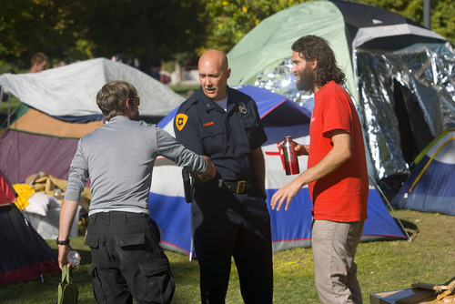 Al Hartmann  |  The Salt Lake Tribune
Salt Lake City Deputy Police Chief Mike Brown, right, shakes hands with one of the the Occupy SLC protesters as Aharon Ben Or, right, one of the original organizers, looks on. Brown, along with Police Chief Chris Burbank, stopped by Pioneer Park on Thursday to keep dialogue open with the group.