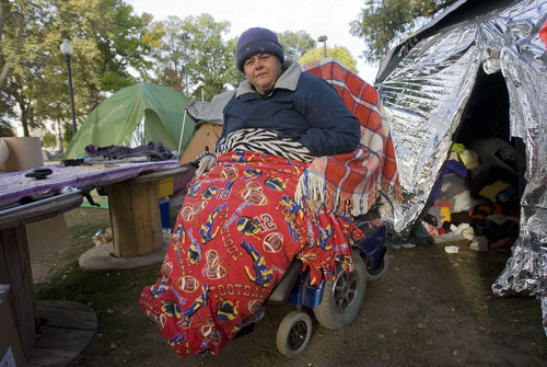 Al Hartmann  |  The Salt Lake Tribune
Cynthia Cook stays warm early Thursday morning at the Occupy Salt Lake camp in Pioneer Park with blankets wrapped around her and her wheelchair.     She spent the night in her donated tent at right.   She fields donations for the camp and keeps track of medical supplies.