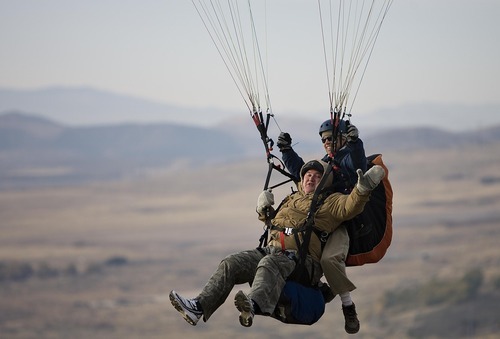 Djamila Grossman  |  The Salt Lake Tribune

Robert Davis, a retired Air Force combat pilot waves as he paraglides with pilot Damion Mitchell at South Side Flight Park, Point of the Mountain in Draper, Utah, on Saturday, Oct. 29, 2011. Davis and other veterans paired up with a pilot of the Utah Hang Gliding and Paragliding Association to fly.