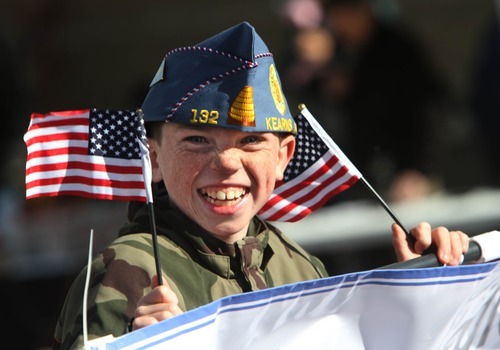 Rick Egan  | The Salt Lake Tribune 
Casey Stocking, 10, holds two flags as he marches in the Veterans Day Parade down 2700 West in Taylorsville Friday.