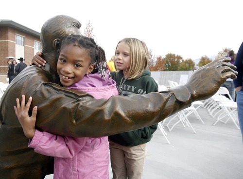 Rick Egan  | The Salt Lake Tribune 
Six-year-old Kayla Nicoll hugs the new statue of a soldier as her friend McKenzie Whitaker, 7, watches after the annual Veterans Day celebration in Taylorsville. The statue was sculpted by Brad Taggart, of Ephriam,