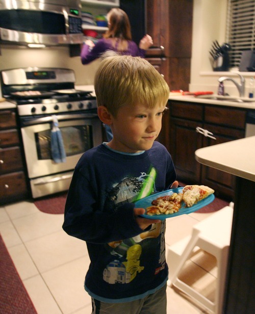 Steve Griffin  |  The Salt Lake Tribune
Luke Oliver, 7, takes his pizza to the table during dinner time at his Salt Lake City home Wednesday, Nov. 9. Luke's brother and sister were diagnosed as infants with a rare metabolic disorder and are forced to eat a special diet. Luke's parents, Amy and Brian Oliver, started the nonprofit Intermountain PKU and Allied Disorders Association to raise money for research and offer support to other families. The children can eat only 7 grams of protein per day. Their diet is limited to fruits, vegetables, a medical formula and low-protein breads. Amy measures every bite of food they eat.