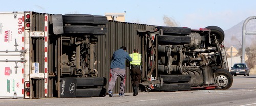 Steve Griffin  |  The Salt Lake Tribune
A motorist and Utah Highway Patrol trooper run to a semitractor trailer that had just been blown over by high winds near Farmington Thursday.