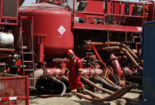 FILE- In this photograph taken April 15, 2009, an unidentified worker steps through the maze of hoses being used at a remote fracking site being run by Halliburton for natural-gas producer Williams in Rulison, Colo. The U.S. Environmental Protection Agency announced Thursday Dec. 8, 2011 in Wyoming, for the first time that fracking - a controversial method of improving the productivity of oil and gas wells - may be to blame for causing groundwater pollution. (AP Photo/David Zalubowski, File)
