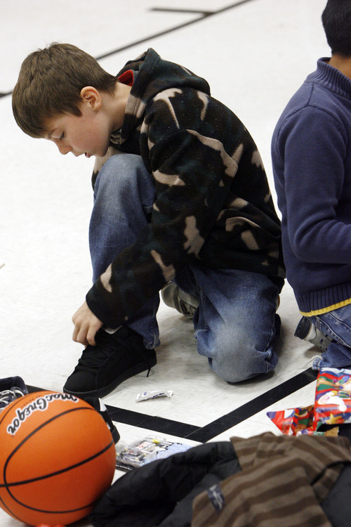 Francisco Kjolseth  |  The Salt Lake Tribune
Lincoln Elementary school student Jessiah Theryn, 11, laces up a new pair of sneakers as he open presents on Thursday, December 15, 2011. Lincoln Elementary School has one of the highest percentages of children – about 95% -- living below the poverty line. Without gifts from the Salt Lake Community and Utah Central Credit Union, these children would not have Christmas. Every child receives the gifts they have personally requested – a 