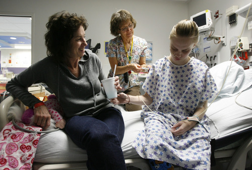 Francisco Kjolseth  |  The Salt Lake Tribune
Paula Birk, left, tries to stay positive with her daughter Megan, 18, as she is given medication by nurse Jennifer Russell and begins to feel nauseous at Primary Children's Medical Center on Wednesday, December 14, 2011. Megan has survived innumerable impossible medical hurdles. From being born severely premature to leukemia to a heart transplant to a recent bout with tumors. Her mother considers her an angel, filled with good, determined to survive.