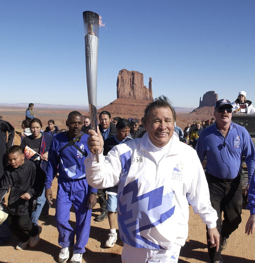 Al Hartmann | Tribune file photo
Legendary distance runner Billy Mills runs the Olympic torch up the final hill to light a cauldron at Monument Valley in the Navajo Tribal Park at the Utah-Arizona state line. Mills shockingly won the 10,000 meters at the 1964 Tokyo Games, becoming the only Native American to win an Olympic gold medal.