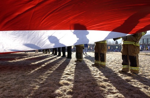 Trent Nelson | Tribune file photo
Firefighters hold a giant American flag at Eccles Coliseum as the torch arrives in Cedar City.