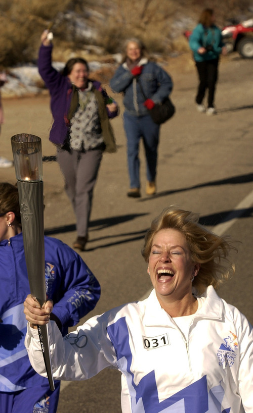 Steve Griffin | Tribune file photo
Moab's Julie Mueller is all smiles as she carries the torch through her hometown.