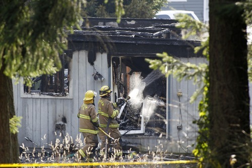 Firefighters spray water on a house near Fredrickson, Wash., Sunday, Feb. 5, 2012, where, according to a sheriff's spokesman, the bodies believed to be Josh Powell and his two sons were found. Days after a judge ruled against him in a child custody hearing, Powell and his sons were killed when police said he appeared to intentionally blow up the house with all three inside ó a tragic ending to a bizarre case that began more than two years ago when the man's wife went mysteriously missing in Utah. (AP Photo/John Froschauer)