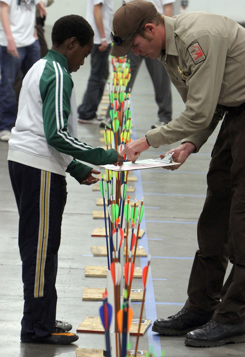 Francisco Kjolseth  |  The Salt Lake Tribune
Sam Iman, 11, of Glendale Middle school is shown how to fill out his archery chart by DNR officer Wyatt Bubak during the Utah State National Archery in the Schools Tournament. The tournament run by the Utah Division of Wildlife, took place at The Salt Palace Convention Center on Saturday, February 11, 2012, as part of the Western Hunting and Conservation Expo.