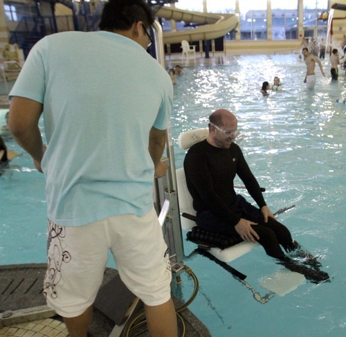 Rick Egan  | The Salt Lake Tribune 

Khoa Tran assists Dave Gillespie, Bountiful, as he uses the lift to enter the pool, at the Holladay Lions Recreation Center, Wednesday, March 14, 2012. Thursday is the compliance deadline for Americans with Disabilities Act design standards.