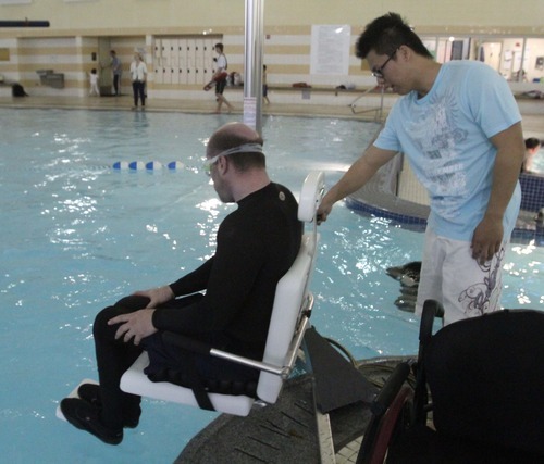 Rick Egan  | The Salt Lake Tribune 

Khoa Tran assists Dave Gillespie, Bountiful, as he uses the lift to enter the pool, at the Holladay Lions Recreation Center, Wednesday, March 14, 2012. Thursday is the compliance deadline for Americans with Disabilities Act design standards.