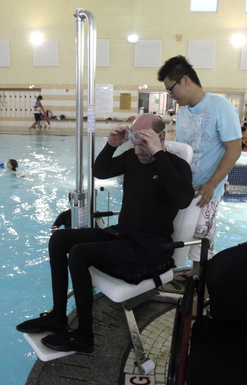 Rick Egan  | The Salt Lake Tribune 

Khoa Tran assists Dave Gillespie, Bountiful, as he transfers to the lift to enter the pool, at the Holladay Lions Recreation Center, Wednesday, March 14, 2012. Thursday is the compliance deadline for Americans with Disabilities Act design standards.