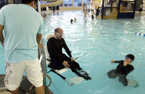 Rick Egan  | The Salt Lake Tribune
Khoa Tran assists Dave Gillespie, Bountiful, as he uses the lift to enter the pool, at the Holladay Lions Recreation Center, Wednesday, March 14, 2012. Thursday is the compliance deadline for Americans with Disabilities Act design standards.
